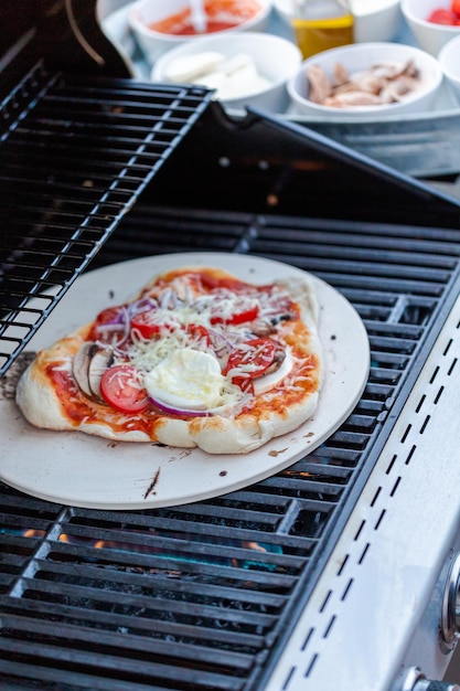 Cocinar pizza en parrilla de gas al aire libre.