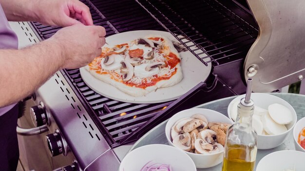 Cocinar pizza en parrilla de gas al aire libre.