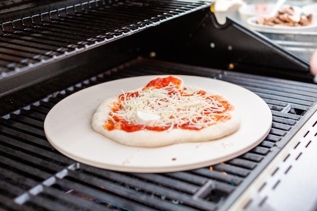 Cocinar pizza en parrilla de gas al aire libre.