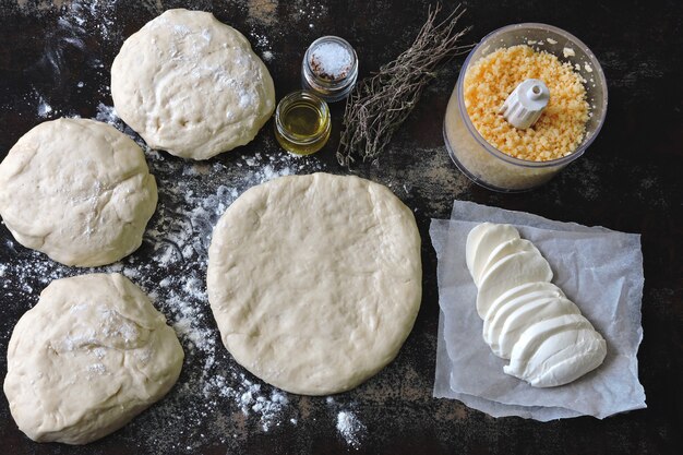 Cocinar pizzas caseras. Masa de pizza, harina, mozzarella y queso rallado. Lay Flat.