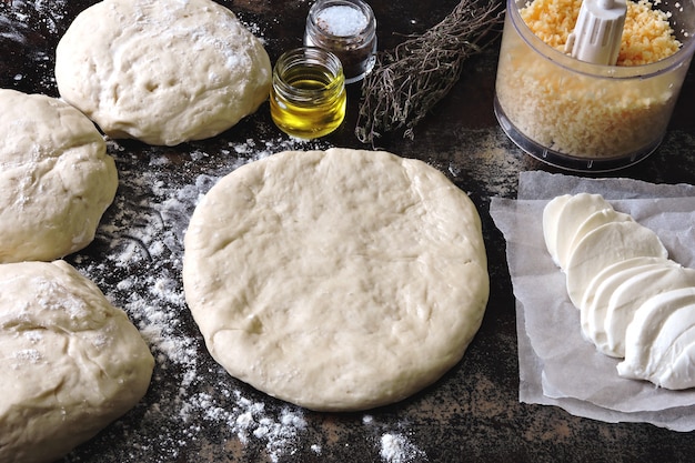 Cocinar pizzas caseras. Masa de pizza, harina, mozzarella y queso rallado. Lay Flat.