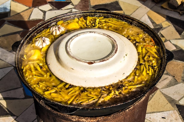 Foto cocinar el plato nacional asiático de arroz pilaf en una olla de metal al aire libre