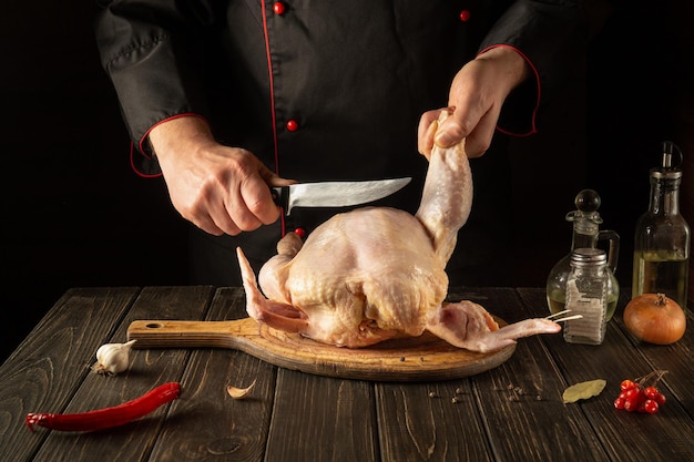 Cocinar pollo en la cocina del restaurante El chef corta el pollo crudo con un cuchillo