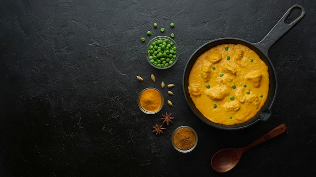 Cocinar sabroso pollo al curry en sartén sobre mesa negra. Vista plana endecha, superior con espacio de copia