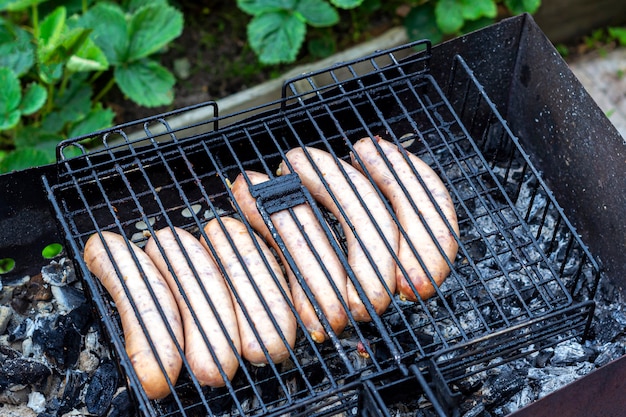 Cocinar salchichas bávaras en una parrilla de barbacoa al aire libre. Picnic, comiendo al aire libre.