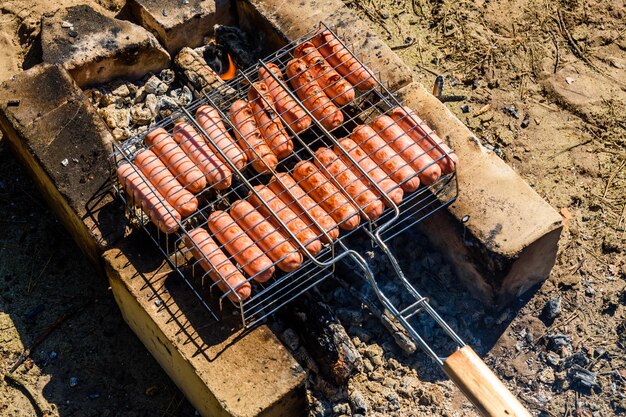 Cocinar salchichas en una parrilla en fogata