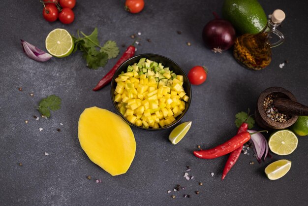 Cocinar salsa de mango con ingredientes cortados en rodajas en un cuenco de cerámica negra