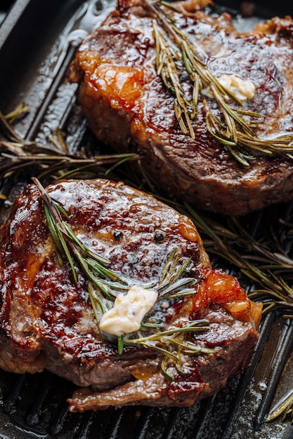 Cocinar suntuosos filetes en una sartén grill con mantequilla untada sobre el filete sazonado con pimienta molida y sal con ramitas de romero