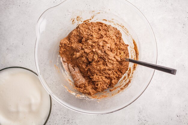 Cocinar la torta de chocolate del vegano con aquafaba en el bol de vidrio, visión superior.