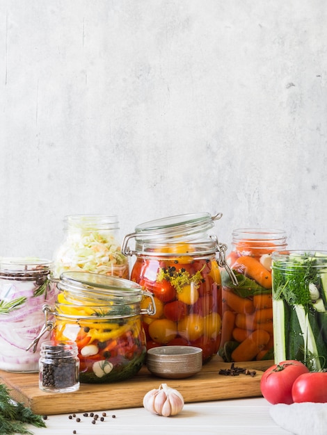 Cocinar verduras en escabeche. Salazón de varios vegetales en frascos de vidrio para almacenamiento a largo plazo. Conserva las verduras en frascos de vidrio. Variedad de vegetales verdes fermentados en tablero de madera