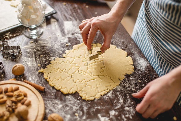 Cocine ama de casa haciendo galletas de Navidad en casa en una colorida cocina