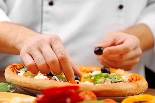 Cocine haciendo una deliciosa pizza en el primer plano del restaurante