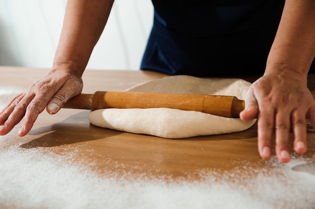 Cocine las manos amasando la masa, espolvoreando un trozo de masa con harina de trigo blanca.