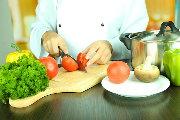 Cocine las manos cortando tomate