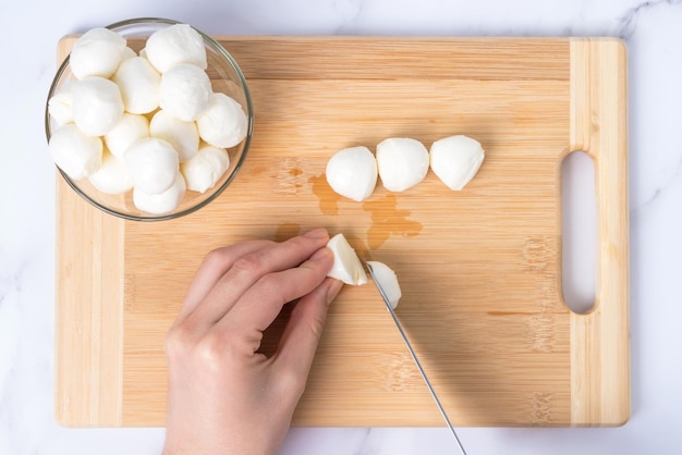 Cocine rebanadas de queso mozzarella en una tabla para cortar