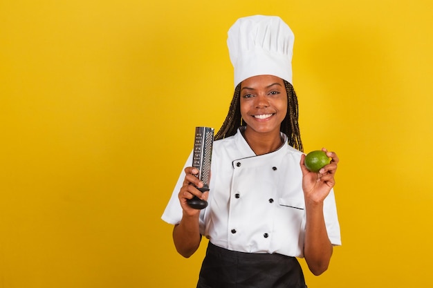 Cocinera afro brasileña joven sosteniendo limón y rallador para cocinar