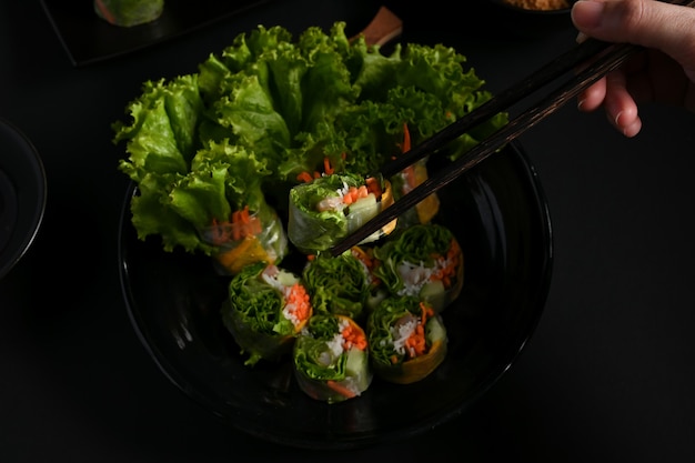 Cocinera agarrando rollitos de primavera vietnamita con palillos