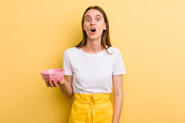 Cocinera bonita adulta joven con un cuenco vacío