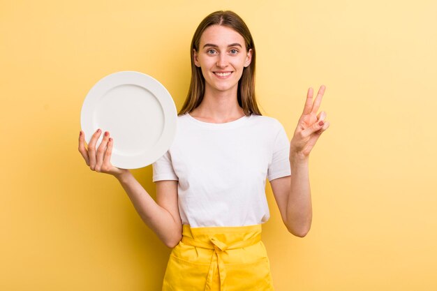 Cocinera bonita adulta joven mujer sosteniendo un plato vacío