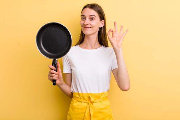 Cocinera bonita adulta joven con una sartén