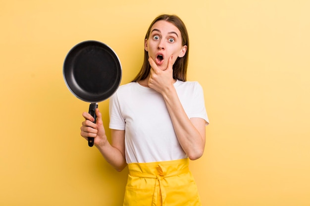 Cocinera bonita adulta joven con una sartén