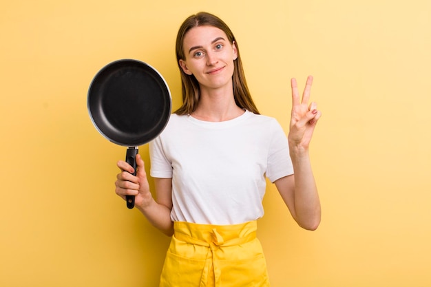 Cocinera bonita adulta joven con una sartén