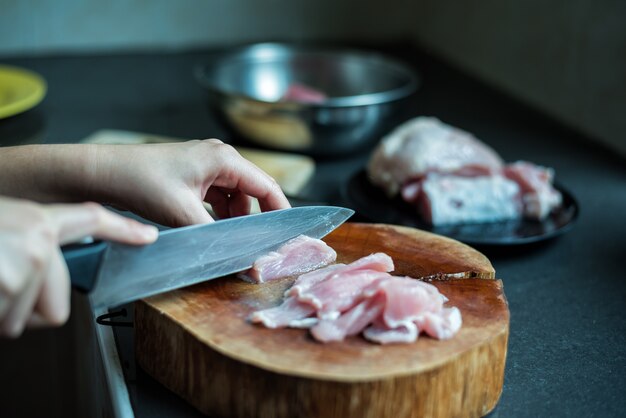 Foto cocinera cortando carne de cerdo en la cocina