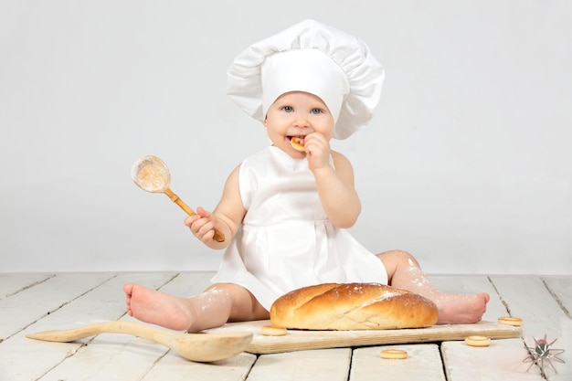 Cocinera infantil Niña vestida de cocinera con un bollo grande y harina La niña tiene un año