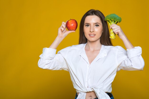 Cocinera sonriente con brócoli verde natural y manzana en la mano Elección saludable de alimentos naturales crudos frescos