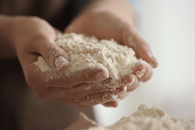 Cocinera sosteniendo harina blanca en las manos en la cocina