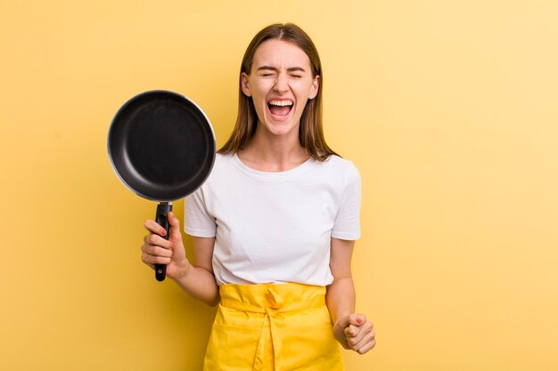 Cocinero adulto joven de la mujer bonita con una cacerola