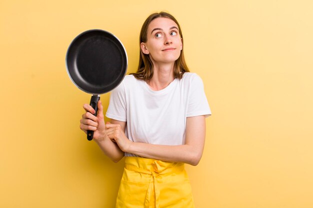 Cocinero adulto joven de la mujer bonita con una cacerola