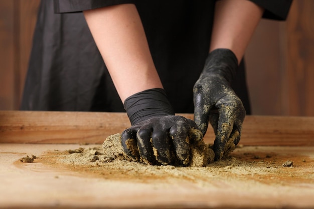 El cocinero amasa la harina de mostaza sobre fondo de madera