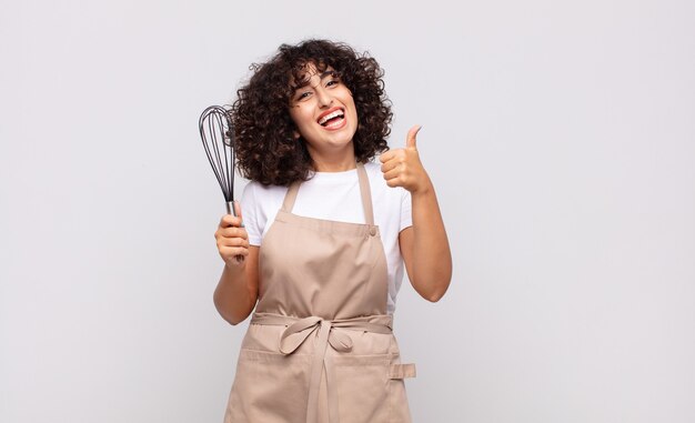 Cocinero árabe de la mujer bonita que lleva un delantal.