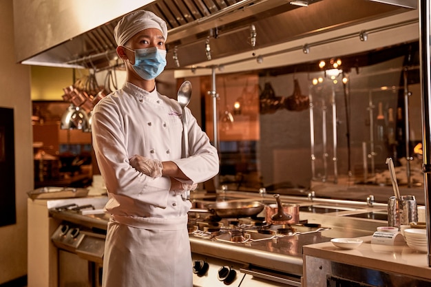 Cocinero asiático cruzando los brazos y mirando a distancia