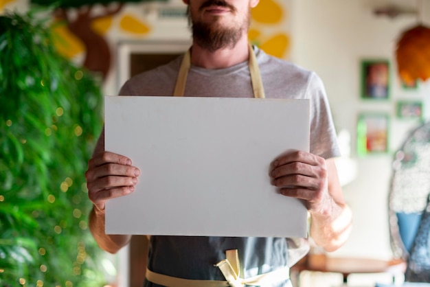 Un cocinero barbudo en delantal sosteniendo un espacio de copia de marco blanco