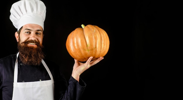 Cocinero barbudo en uniforme de chef y delantal con calabaza saludable cosecha orgánica vegetal comida de otoño