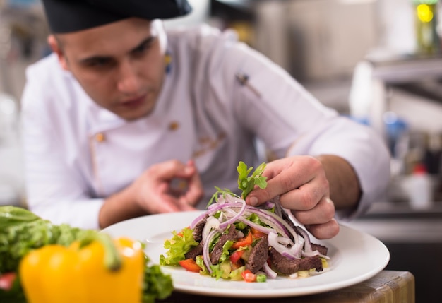 Cocinero chef decorando guarnición plato de comida preparada en el plato en el restaurante cocina comercial