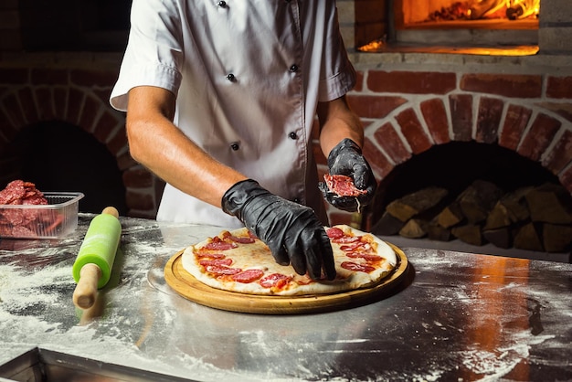 Cocinero Chef haciendo deliciosa pizza en el primer plano del restaurante