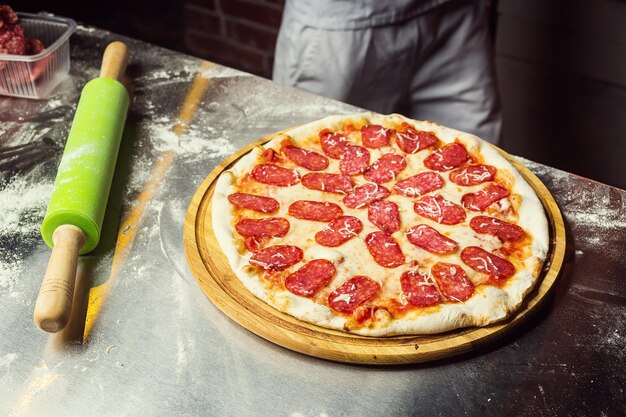 Cocinero Chef haciendo deliciosa pizza en el primer plano del restaurante