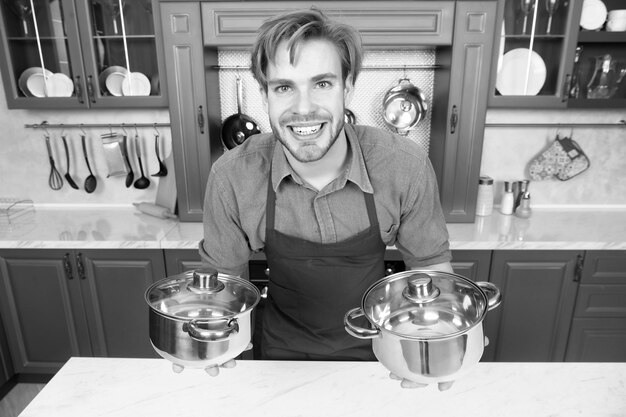 Cocinero chef masculino sonriente sosteniendo sartenes