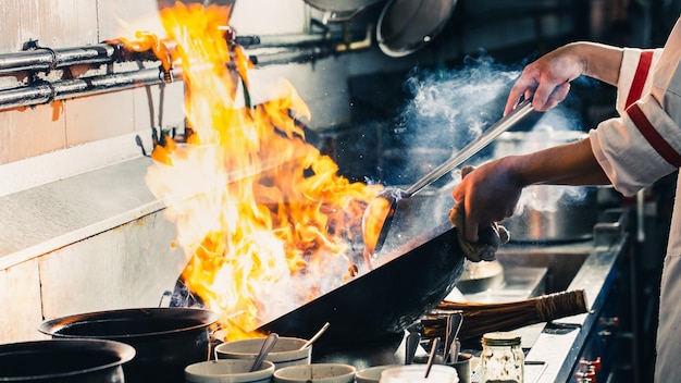Cocinero cocinando en la cocina cocinero profesional cocinando en el fuego del restaurante