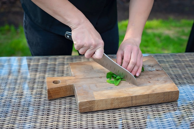 El cocinero del cocinero corta verdes en una tabla de madera.