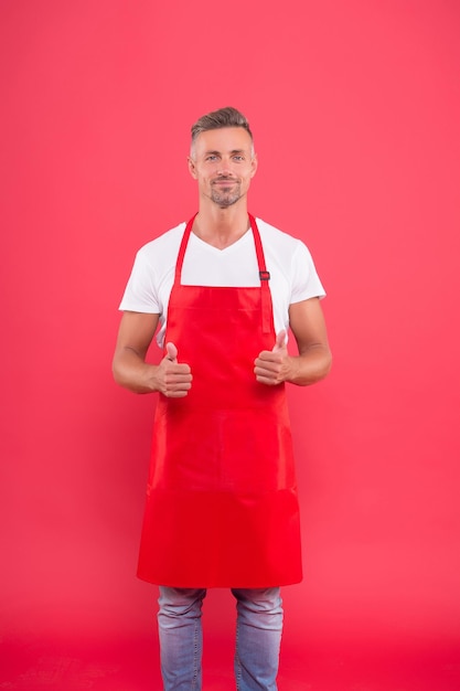 Cocinero cocinero masculino en delantal rojo. delantal de desgaste empresario en cafetería. su obra favorita. Retrato de guapo chef profesional. sonriente hombre chef muestra el pulgar hacia arriba. Se busca chef profesional.