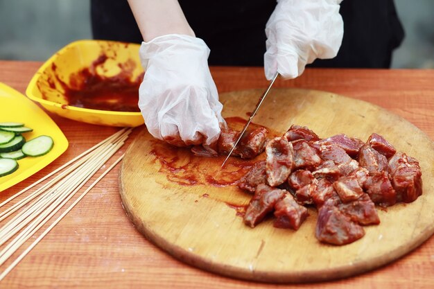 El cocinero corta carne para cocinar barbacoa en la mesa.