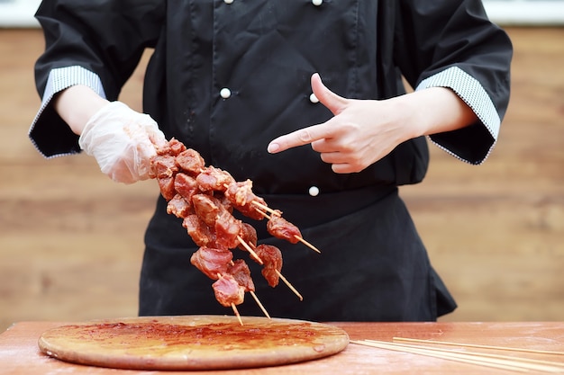 El cocinero corta carne para cocinar barbacoa en la mesa.