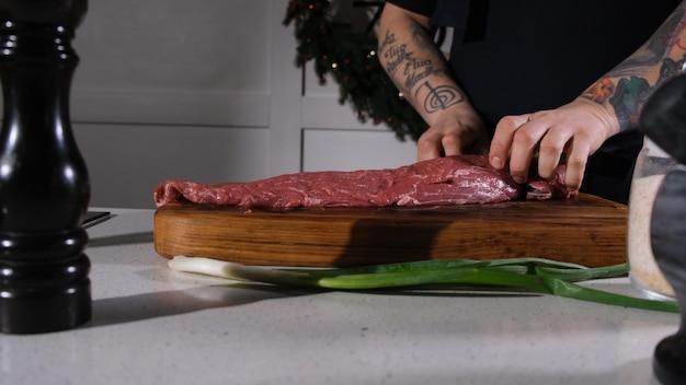 El cocinero corta la carne de res con un cuchillo en una tabla de cortar el chef separa el entrecote de un pedazo de carne fresca