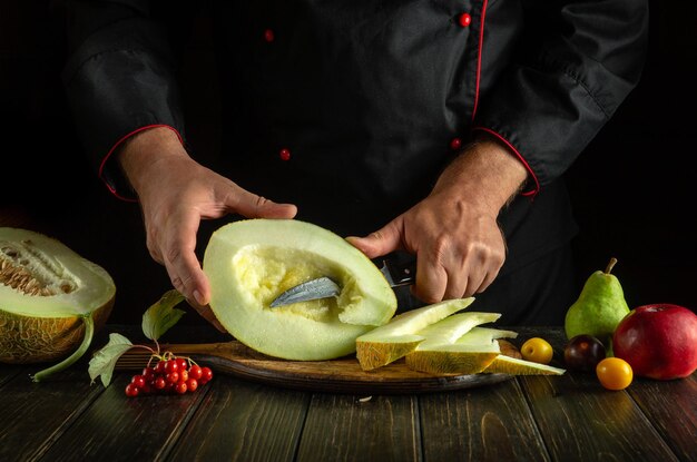 El cocinero corta el melón en rebanadas en una tabla de madera en la cocina El concepto de una dieta de frutas en una cocina de restaurante cocina nacional asiática