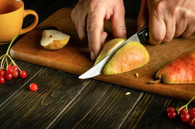 El cocinero corta una pera madura en una tabla de cortar para preparar compota o jugo de fruta Dieta de peras para un conjunto de vitaminas