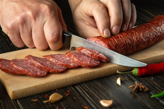 El cocinero corta la salchicha en trozos pequeños para hacer sándwiches Idea de comida callejera